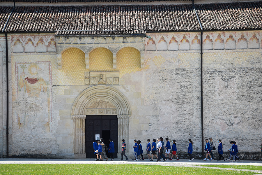 A line of schoolchildren enters the large doorway of the Duomo di Santa Maria Maggiore Cathedral in Spilimbergo.