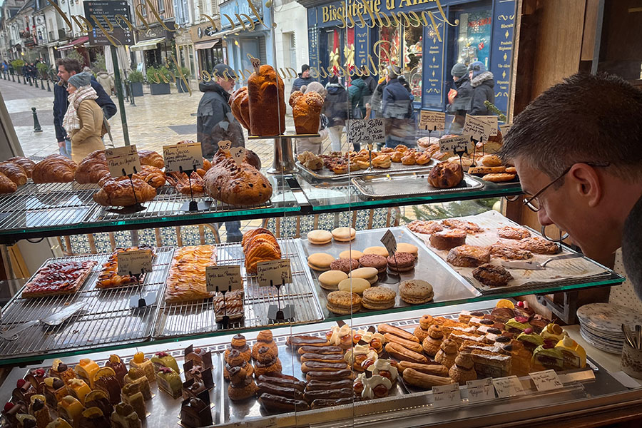 A display window at a pastry shop in Amboise, France is full with macarons, éclairs, slices of a bûche de Noël, croissants, and brioche.