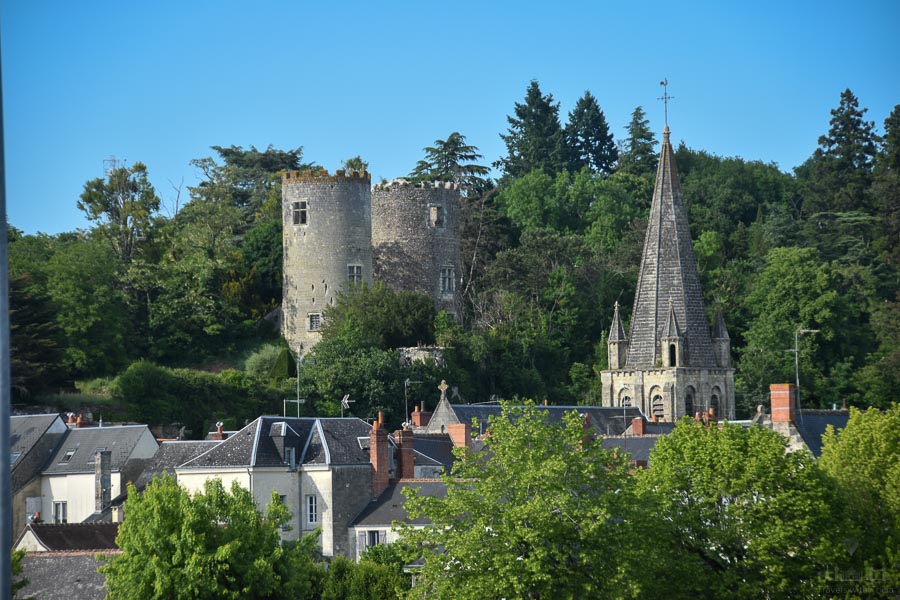 In the French town of Cinq Mars la Pile, the church steeple and castle towers rise about the town's rooftops.