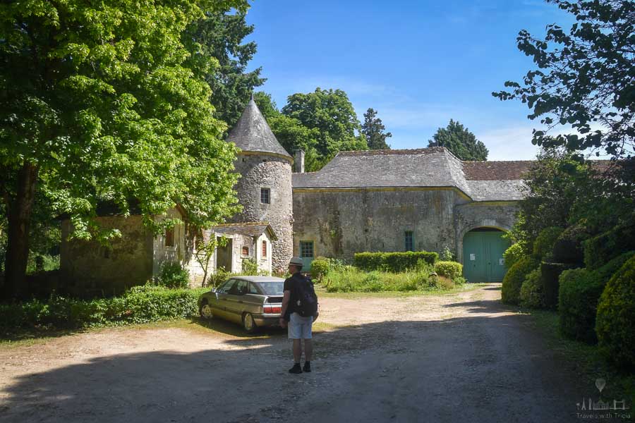 The driveway of the Château de Cinq-Mars is overlooked by leafy trees and a round stone tower.