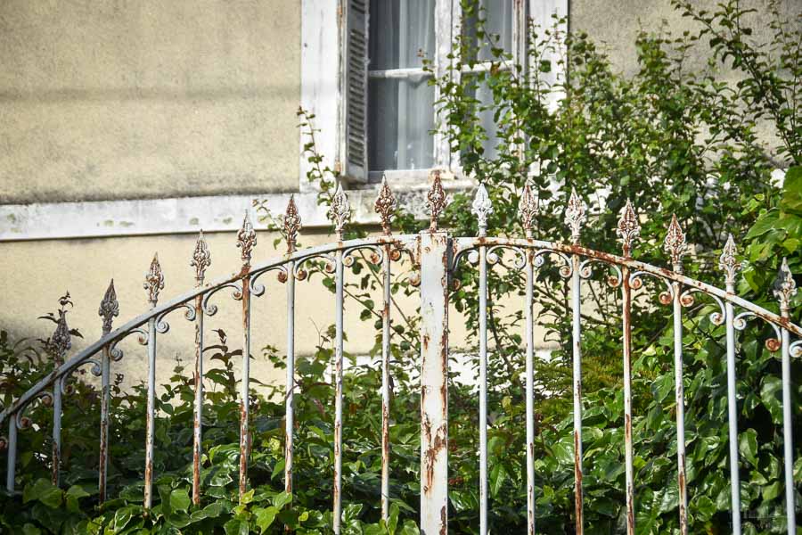 A white, and partially rusty ornamental gate in front of a home in Cinq Mars la Pile, France..