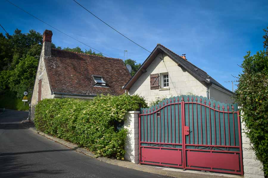 A stone home with a green and red gate in Cinq Mars la Pile, France.