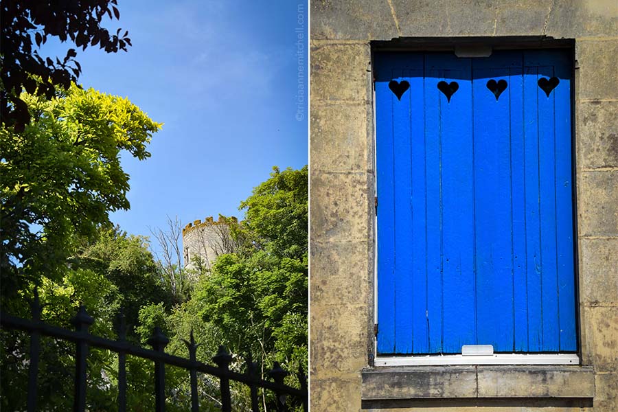 On the left, a round tower rises above the treetops in the French town of Cinq Mars la Pile. On the right, a closed set of blue shutters with heart cut-outs adorn a stone home.